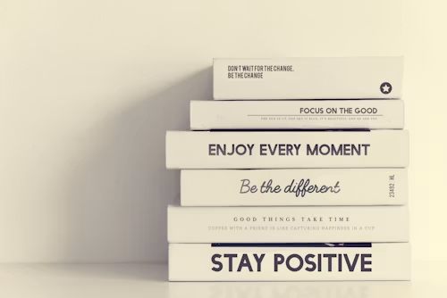 Books stacked with the words Be the different and Stay positive