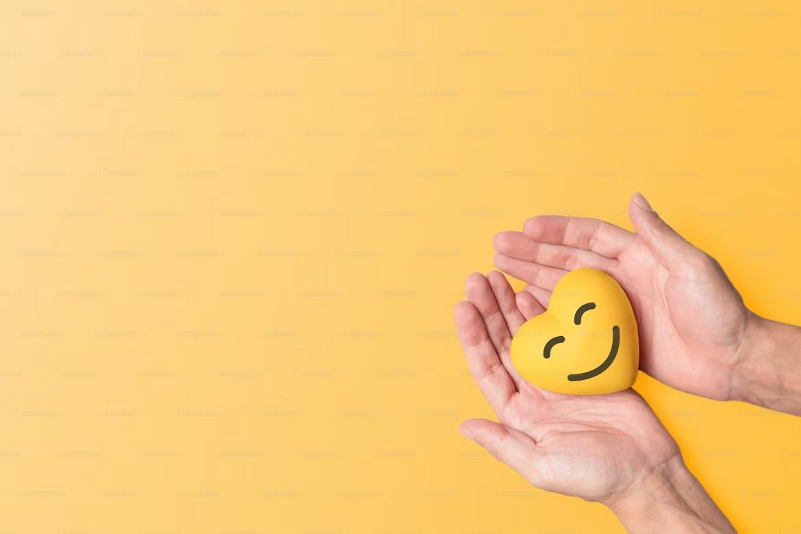 Hands holding a smiling yellow heart