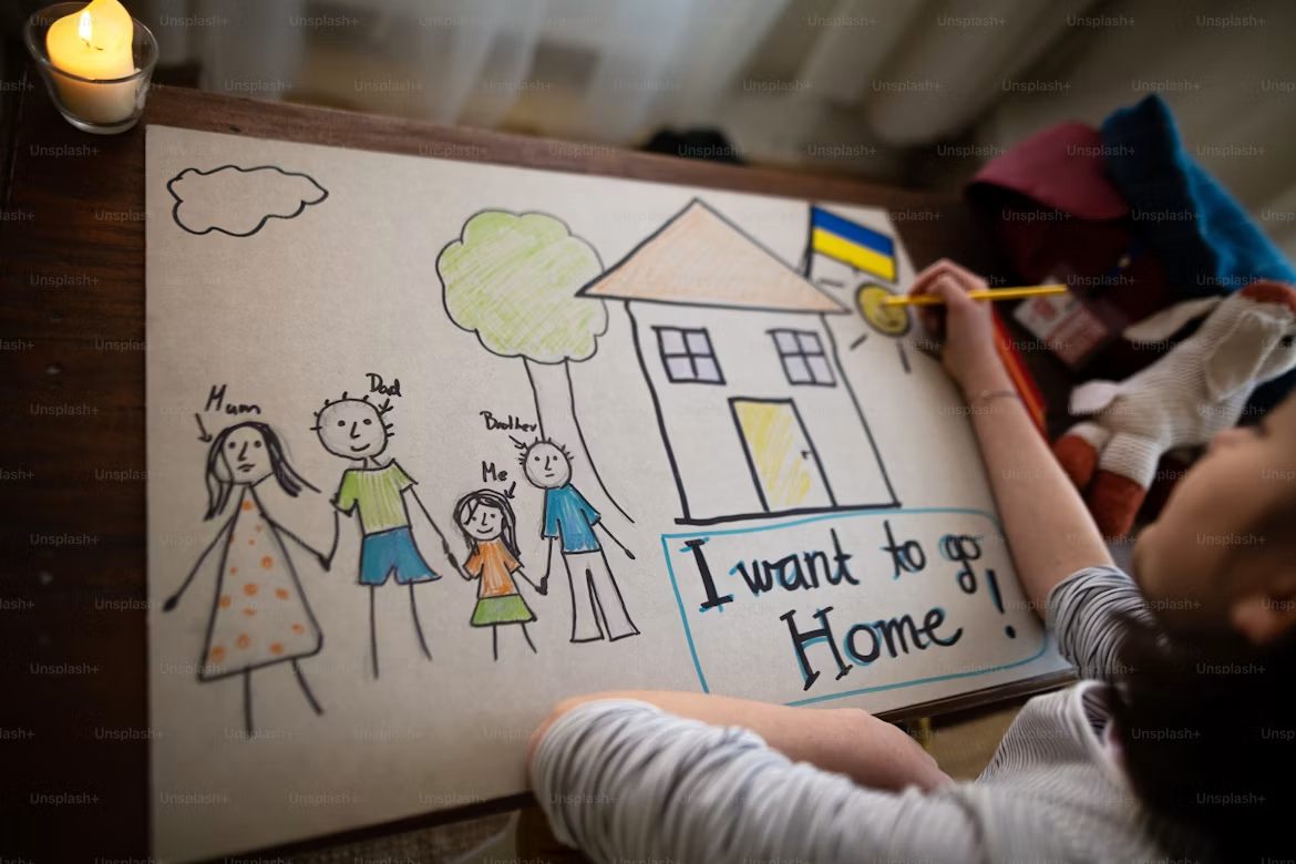 A child drawing a house with the words I want to go home