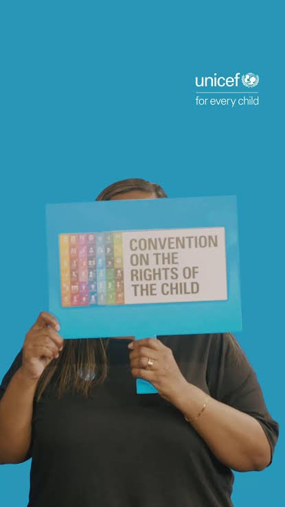 A person holding up a sign saying Convention on the Rights of the Child